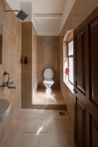 a bathroom with a toilet and a sink and a window at Hideaway Art Residency in Ooty