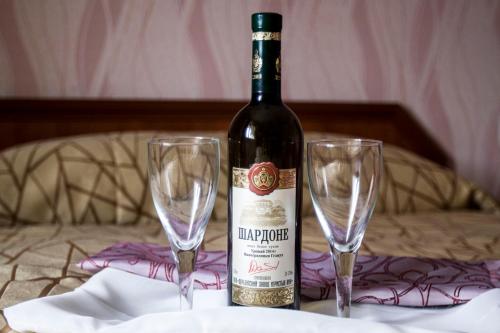 a bottle of wine next to two glasses on a table at Motel Lesnoy in Odintsovo