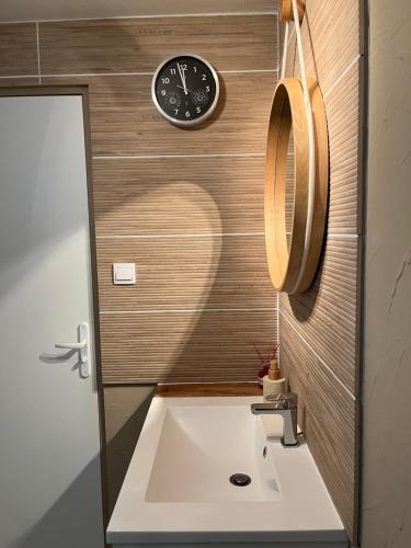 a bathroom with a sink and a clock on the wall at Chez Val et Phil in La Voulte-sur-Rhône