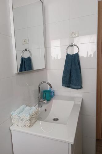 a bathroom sink with a mirror and blue towels at The Pearl in Sha‘alvim