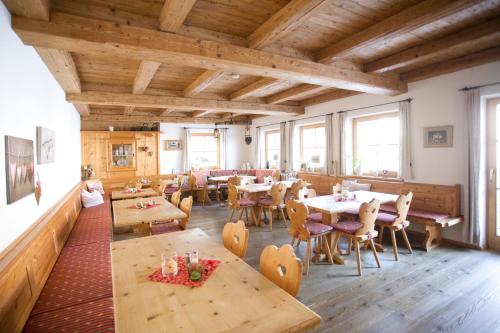 un restaurante con mesas y sillas de madera y ventanas en Beim Nuihausa en Reit im Winkl