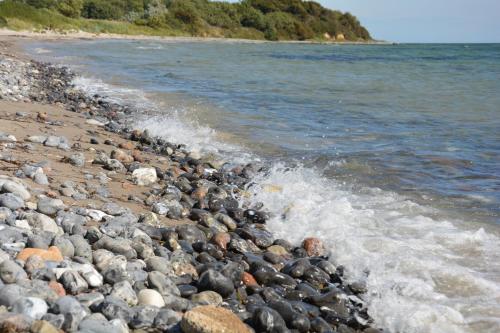 a group of rocks on a beach near the water at Havehøjegaard in Borre