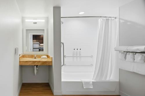a white bathroom with a shower and a sink at TownePlace Suites Farmington in Farmington