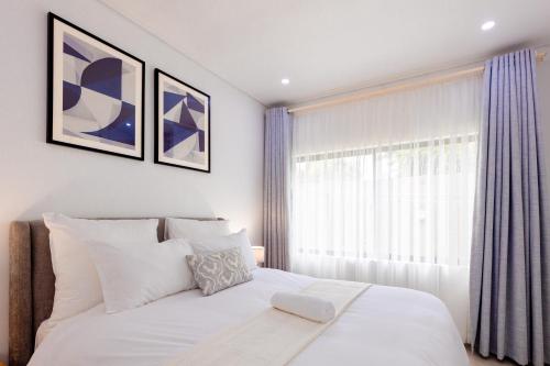 a bedroom with a white bed and a window at Elle Apartments in Lusaka