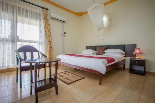 een slaapkamer met een bed, een tafel en een stoel bij Askay Hotel Suites in Entebbe