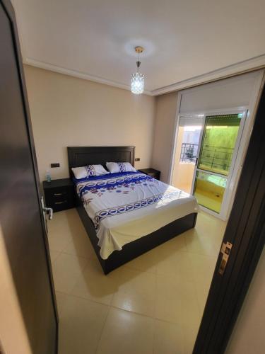 a bedroom with a bed and a large window at appartement NADOR wifi gratuit clima mobile in Selouane