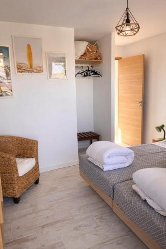 a bedroom with two beds and a chair at Maison classée à 100m de l'océan in Mimizan-Plage