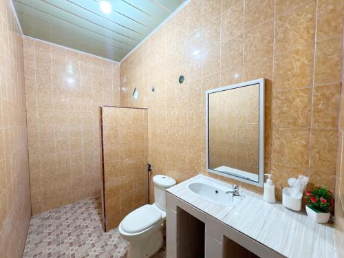 a bathroom with a toilet and a sink and a mirror at Harus Damai Inn in Lagudri