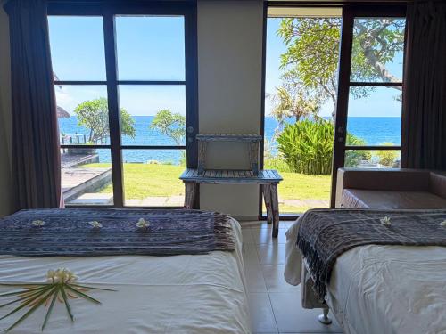 two beds in a room with a view of the ocean at Villa Bukit Segara in Amed