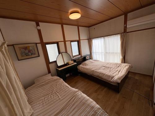 a bedroom with two beds and a mirror in it at AppleHouse高瀬駅 in Mitoyo