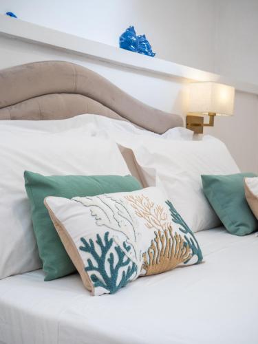 a white bed with green and white pillows on it at Syrene Suites Sorrento in Piano di Sorrento