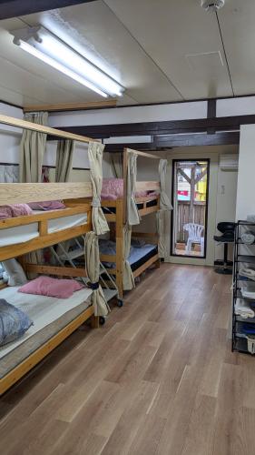 a room with several bunk beds and a wooden floor at 奄美ザナゼステイTheNazeStay in Amami