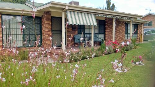 a house with a lawn with flowers in front of it at Butterfly Cottage in Tumut