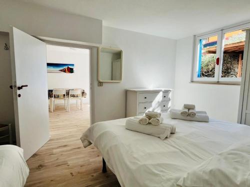 ein weißes Schlafzimmer mit zwei Betten, auf denen Handtücher liegen in der Unterkunft Bocca D'oro S1 in Isola del Giglio