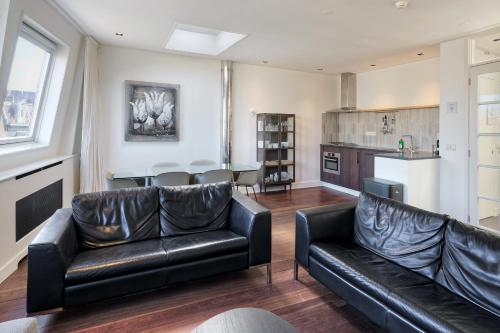 a living room with two leather couches and a kitchen at Marnix360apartments Jordaan in Amsterdam