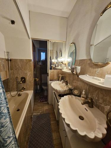 a bathroom with two sinks and a tub and two mirrors at Lake apartment with terrace in Nidau