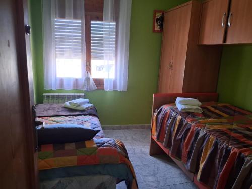 a green room with two beds and a window at Casa Nasarre- Acogedora casa rural con garaje con vistas a la Sierra de GUARA in Abiego