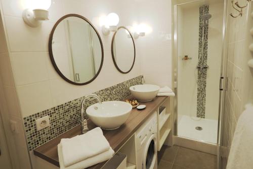 ein Badezimmer mit zwei Waschbecken, einem Spiegel und einer Dusche in der Unterkunft Louvre Opera Classic ChicSuites in Paris