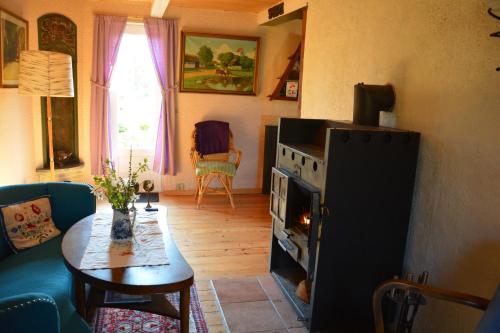 a living room with a table and a fire in a stove at Havehøjegaard in Borre