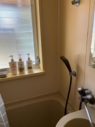 a bathroom with a sink and a window next to a tub at AppleHouse高瀬駅 in Mitoyo