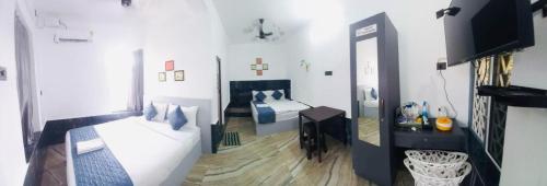 a white room with a bed and a television at Hotel Bougainvillea in Cochin