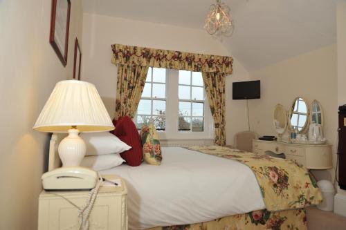a bedroom with a bed with a lamp and a window at The Inglenook Hotel in Bognor Regis