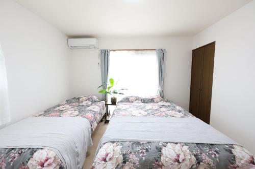 two beds in a room with a window at Nagoya Kuwana Choco House in Yatomi 