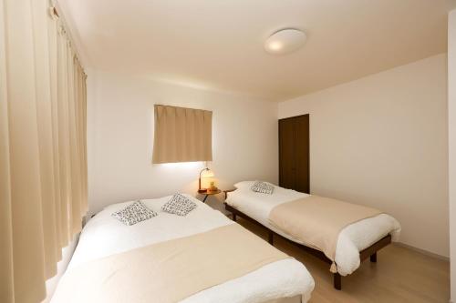 two beds in a room with white walls at Nagoya Kuwana Choco House in Yatomi 