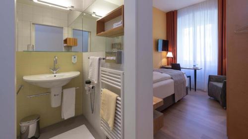 a small bathroom with a sink and a bed at Hotel Fravi in Andeer