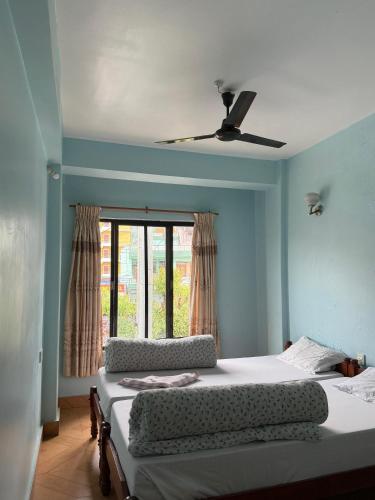 a bedroom with a bed with a ceiling fan at Hotel Unicorn in Pokhara