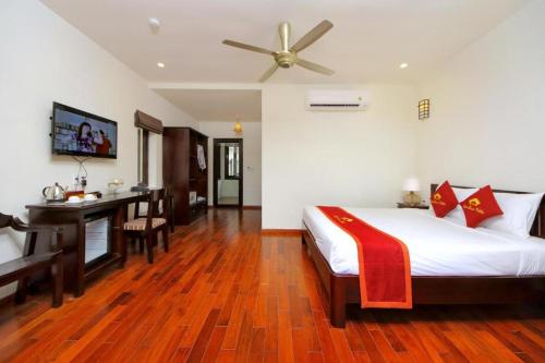 a bedroom with a bed with a desk and a ceiling fan at Little Town Villa in Hoi An