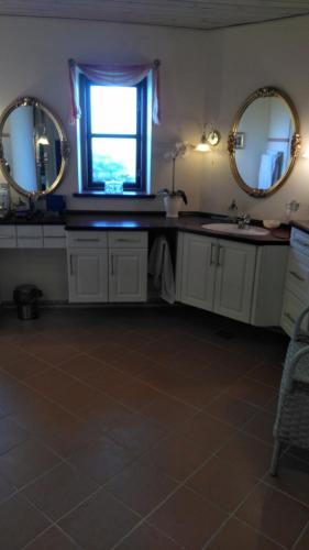 a bathroom with two mirrors and a sink and a window at Romantik og idyl in Dybvad