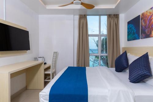 a bedroom with a bed and a desk and a window at White Harp Beach in Hulhumale