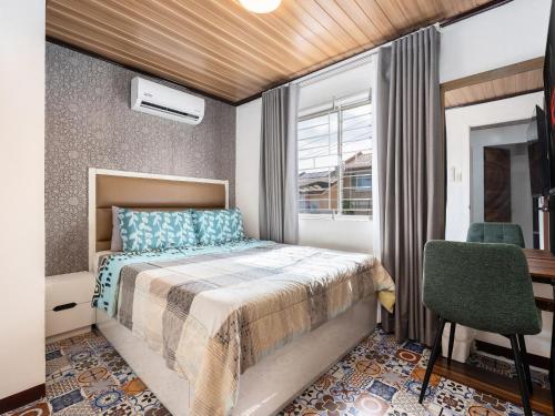 a bedroom with a bed and a desk and a window at Bella Casa (3BR House at Azienda Genova) in Talisay
