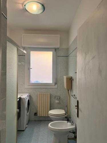 a bathroom with a white toilet and a window at Beach 300m Piazza Milano in Lido di Jesolo