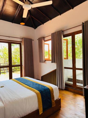 a bedroom with a large bed and windows at Aria Resort in Sigiriya