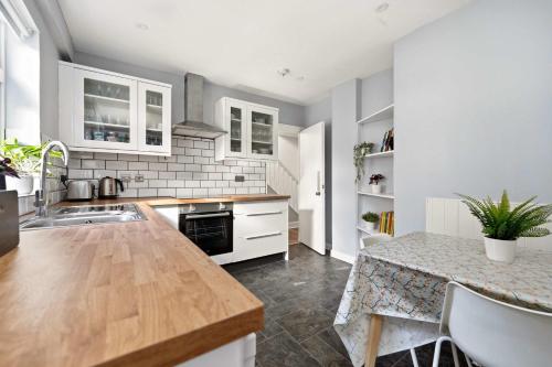 a kitchen with white cabinets and a wooden counter top at 4-Bed Home Central Location & Garden in Oban