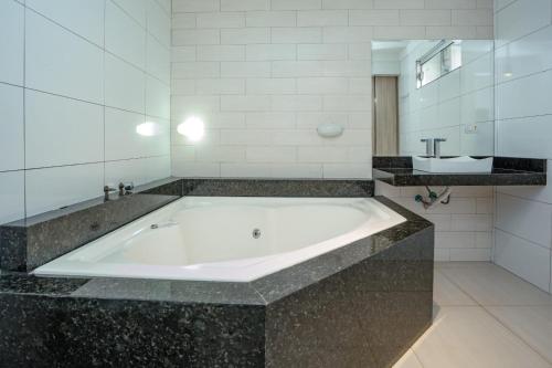 a large bath tub in a bathroom with a sink at Sobrado Jardim Real in Maringá