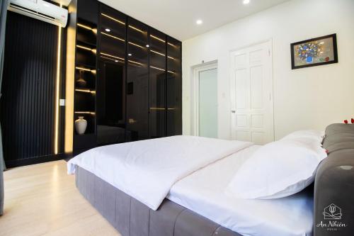 a bedroom with a white bed and a black closet at An Nhiên House in Kon Rung (1)