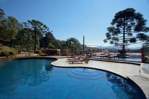 una gran piscina con bancos y mesas en un patio en Fazenda Hotel Itapuá, en Monte Verde