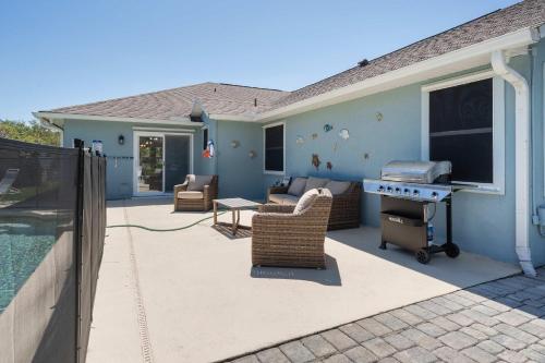 a patio with a grill and chairs next to a house at Spacious 5BR Pool Oasis Near Disney Resort in Sebastian