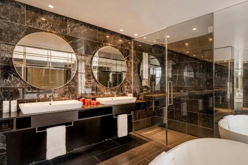 a bathroom with two sinks and two mirrors at The Dean Munich, Autograph Collection in Munich
