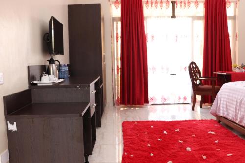 a bedroom with a bed and red curtains and a red rug at White Peacock Resort Mtwapa in Mombasa