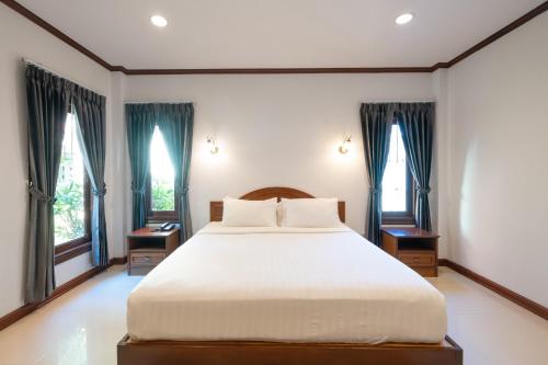a bedroom with a large bed and two windows at The Green Beach Resort in Sam Roi Yot