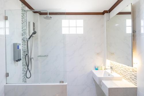 a white bathroom with a shower and a sink at The Green Beach Resort in Sam Roi Yot