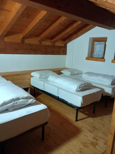 three beds in a room with wooden ceilings at Castle house in Aprica
