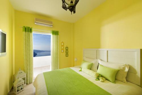 a bedroom with a green bed with a large window at Santorini Roses Suites in Imerovigli