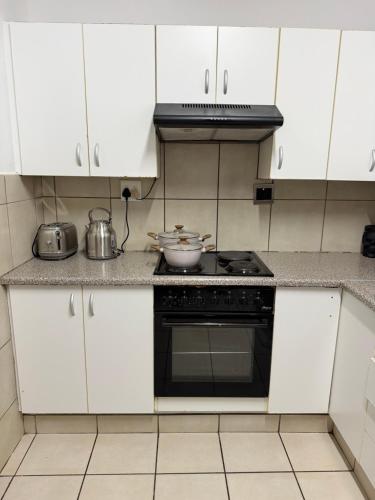 a kitchen with white cabinets and a stove top oven at Vellora Haus in Burgersfort
