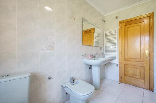 a bathroom with a sink and a toilet and a mirror at Casa Outeiro in Encinedo