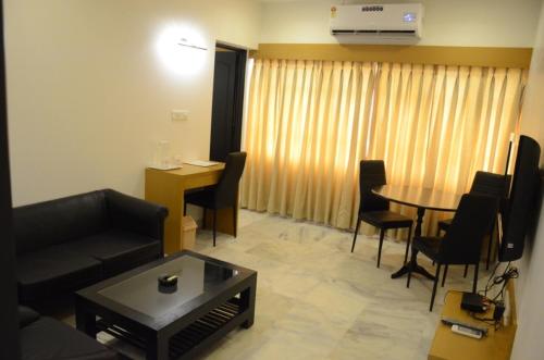 a living room with a couch and a table and chairs at Hotel Yuvraj in Vadodara